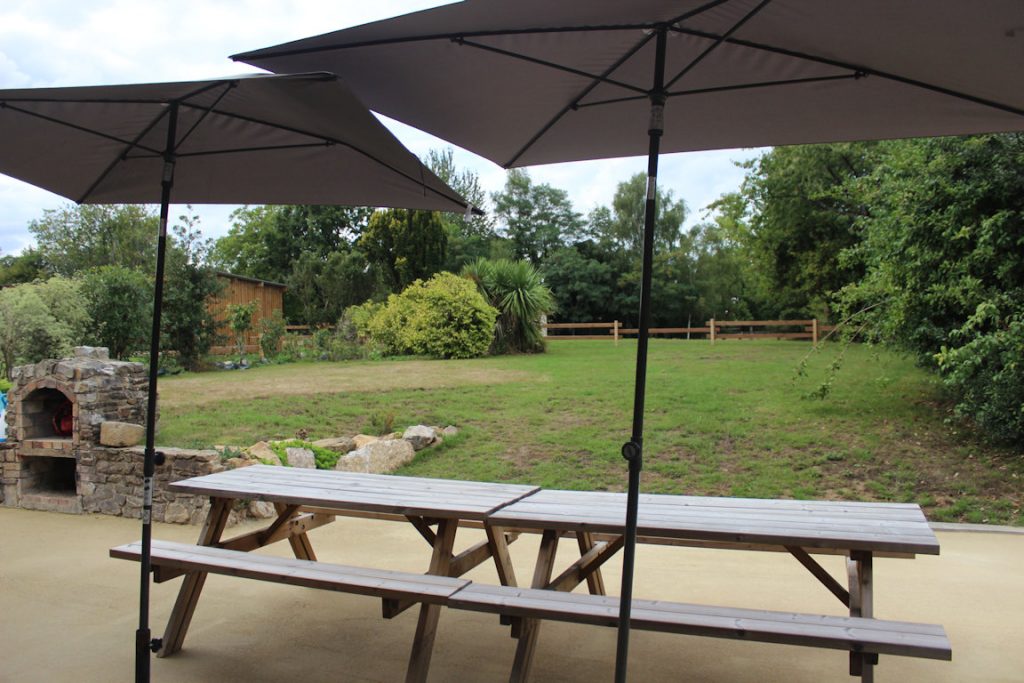 Vue du jardin arrière du gîte 15 personnes à Rennes, avec pelouse, salon de jardin et haie, idéal pour se détendre au Domaine de Beauregard (35)